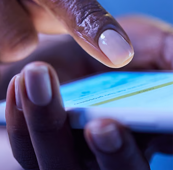 A close-up of a hand using a smartphone touchscreen, with a finger pointing at the display, captures everyday digital life in Africa.