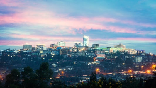 City skyline at dusk with a pink and blue sky, lights glowing on buildings and streets below, capturing the vibrant nightlife of an African metropolis.