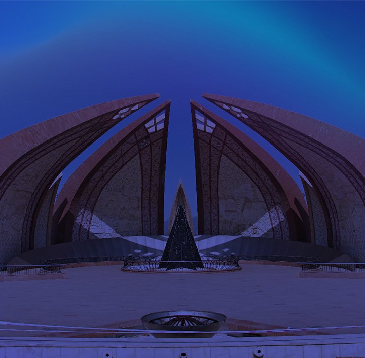 A night view of the Pakistan Monument in Islamabad, featuring four large, flower petal-shaped structures arching inward, with intricate carvings visible. The sky above is deep blue, and the foreground shows a wide, empty plaza.