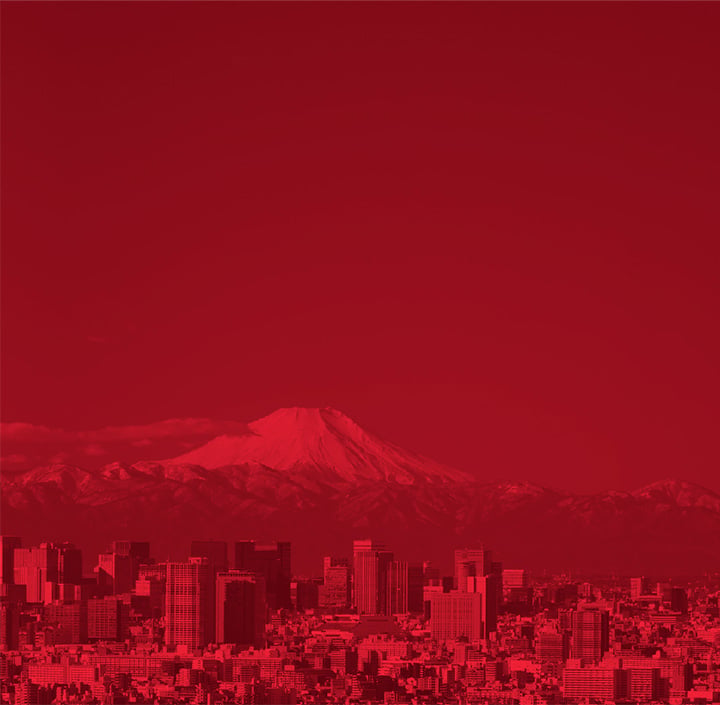 A city skyline with tall buildings stands in the foreground, whilst Mount Fuji with a snow-capped peak rises in the background, capturing the essence of Asia Pacific. The entire image has a red colour filter, giving it a monochromatic appearance.