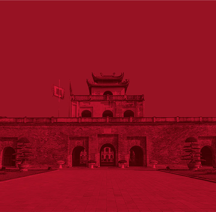 A historic stone fortress with arched gateways and a flag, tinted in a red monochrome, evokes the timeless charm of Asia Pacific heritage.