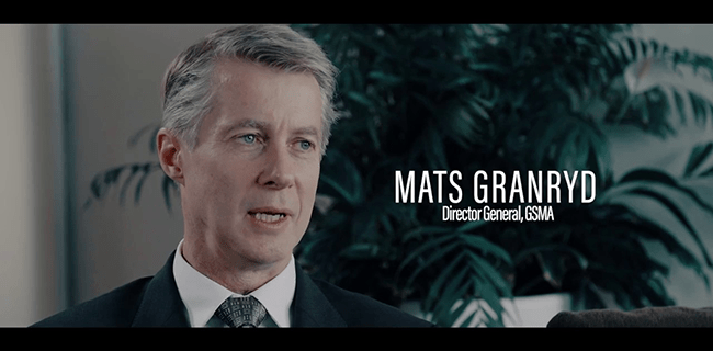 A man with light gray hair in a suit and tie sits indoors, speaking. White text reads “Mats Granryd, Director General, GSMA.” A large green plant is blurred in the background. The lighting is soft and professional.