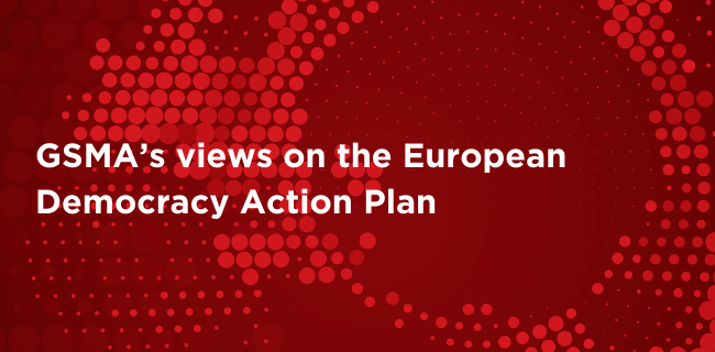 White text on a red background with a circular pattern of large and small dots. The text reads: “GSMA’s views on the European Democracy Action Plan.” The red background fades subtly and the dotted pattern adds visual interest.