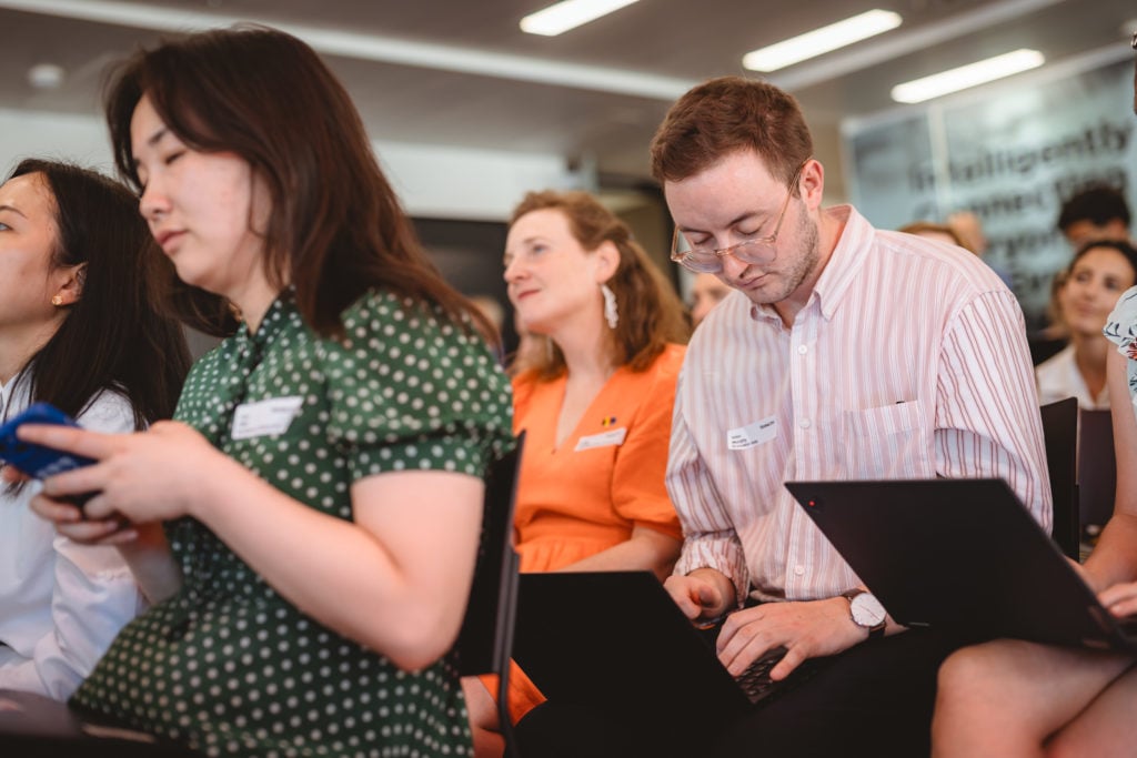 A group of people sitting in chairs using laptops.