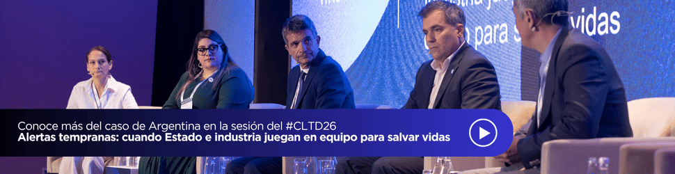 Cinco personas vestidas con traje de negocios están sentadas en una mesa redonda en el escenario, participando en un debate. En una gran pantalla situada detrás de ellas se muestra el título de la sesión, que trata sobre los sistemas de alerta temprana de Argentina y la colaboración entre el Estado y la industria para salvar vidas. Una de ellas está hablando con un micrófono de mano.