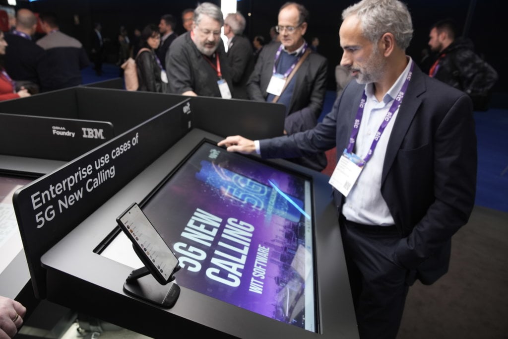 A professional presentation about enterprise use cases of 5g on a large interactive display at a conference with interested attendees observing.
