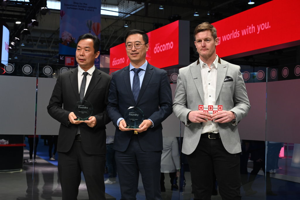 Three men in business attire holding awards at an event.