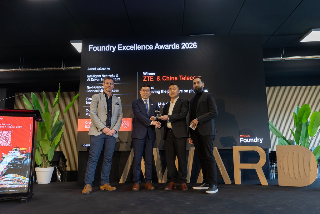 Four men in suits stand on stage holding an award, with a screen behind reading "Foundry Excellence Awards 2026.