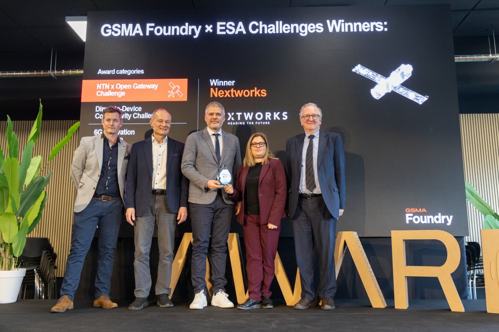 Five people stand on stage holding an award at the GSMA Foundry × ESA Challenges Winners event.