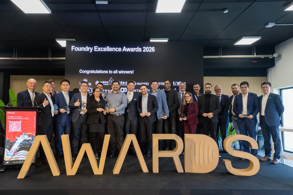 A group of people holding awards stand behind large letters spelling "AWARDS" at an event.