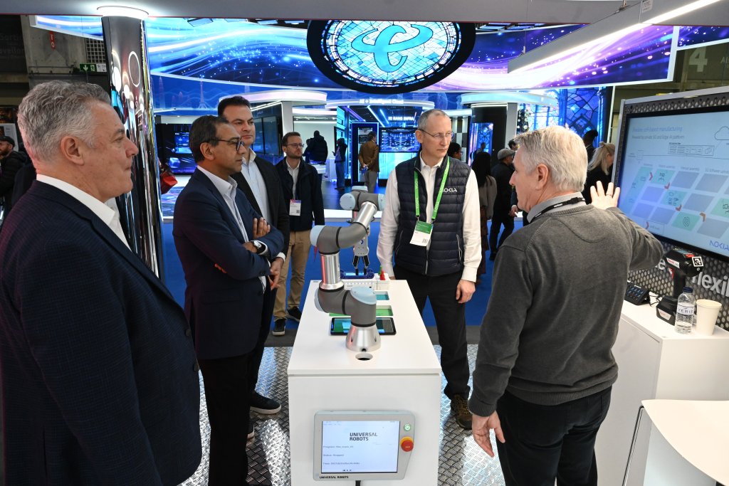 Five men stand around a robotics display at a technology exhibition, engaging in discussion.