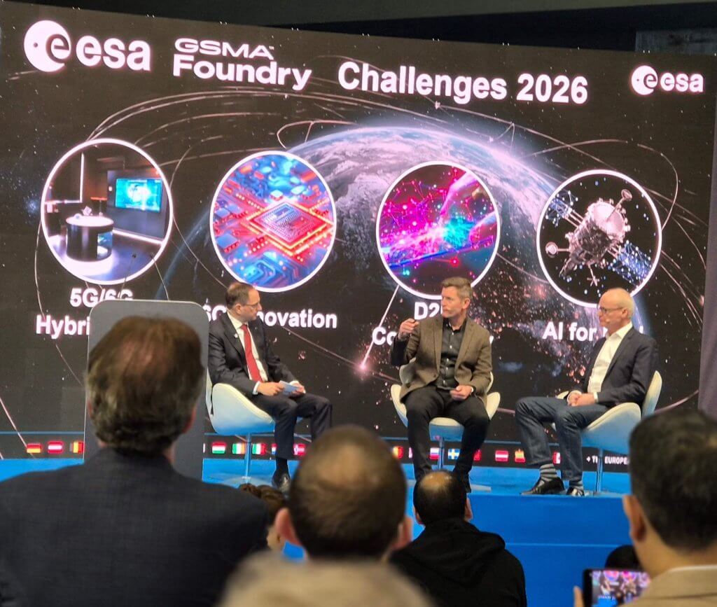 Three men discuss space technology on stage under a screen labeled "ESA and GSMA Foundry Challenges 2026," featuring futuristic graphics.