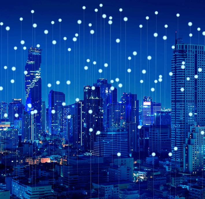 A city skyline at night with glowing dots and lines representing digital connectivity.