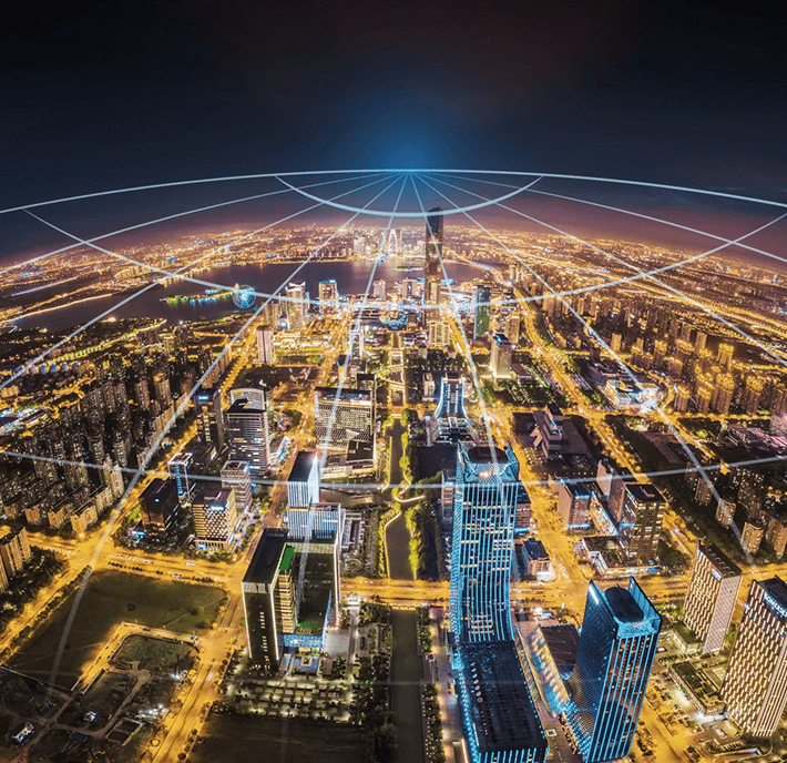Aerial view of a city at night with digital lines representing global connectivity across the skyline.