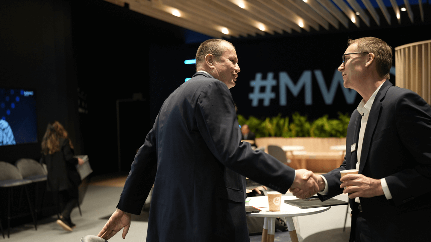 Two men shaking hands in a conference room.