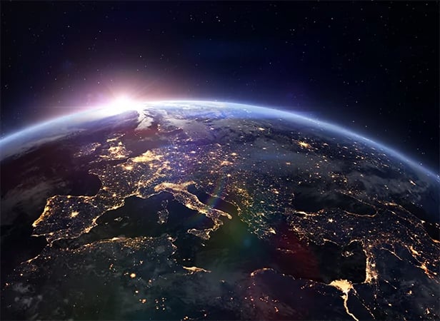 View of Earth from space at night showing parts of Europe and Africa, city lights illuminating the continents. The horizon glows with sunrise, while stars dot outer space—a perspective reminiscent of member gateway features connecting the world.