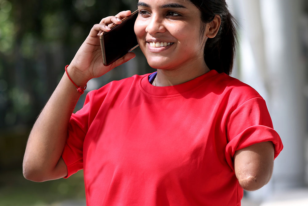 A young Indian woman with an amputated left arm using a smartphone