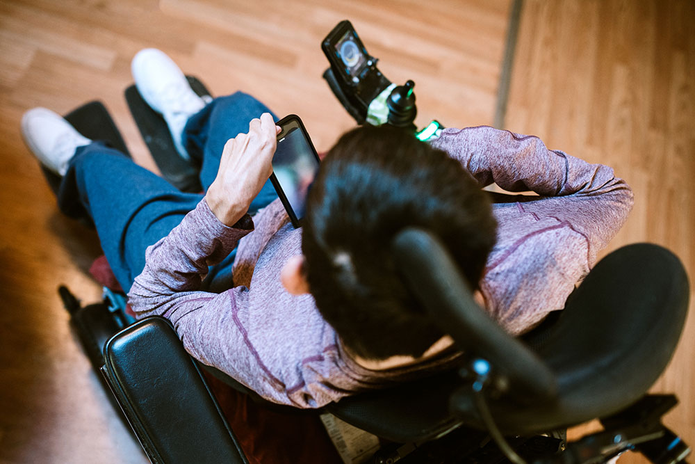 A young adult male with cerebral palsy texts someone on his smartphone, using voice recognition