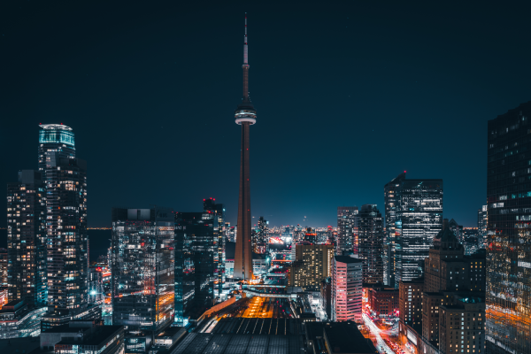 Toronto skyline at night with the CN Tower lit up and city lights illuminating tall buildings.