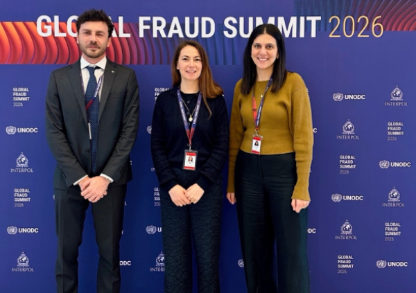 Three people stand in front of a "Global Fraud Summit 2026" backdrop, smiling at the camera.