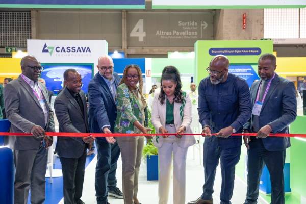Seven people at an event cut a red ribbon together at a Cassava Technologies stand.