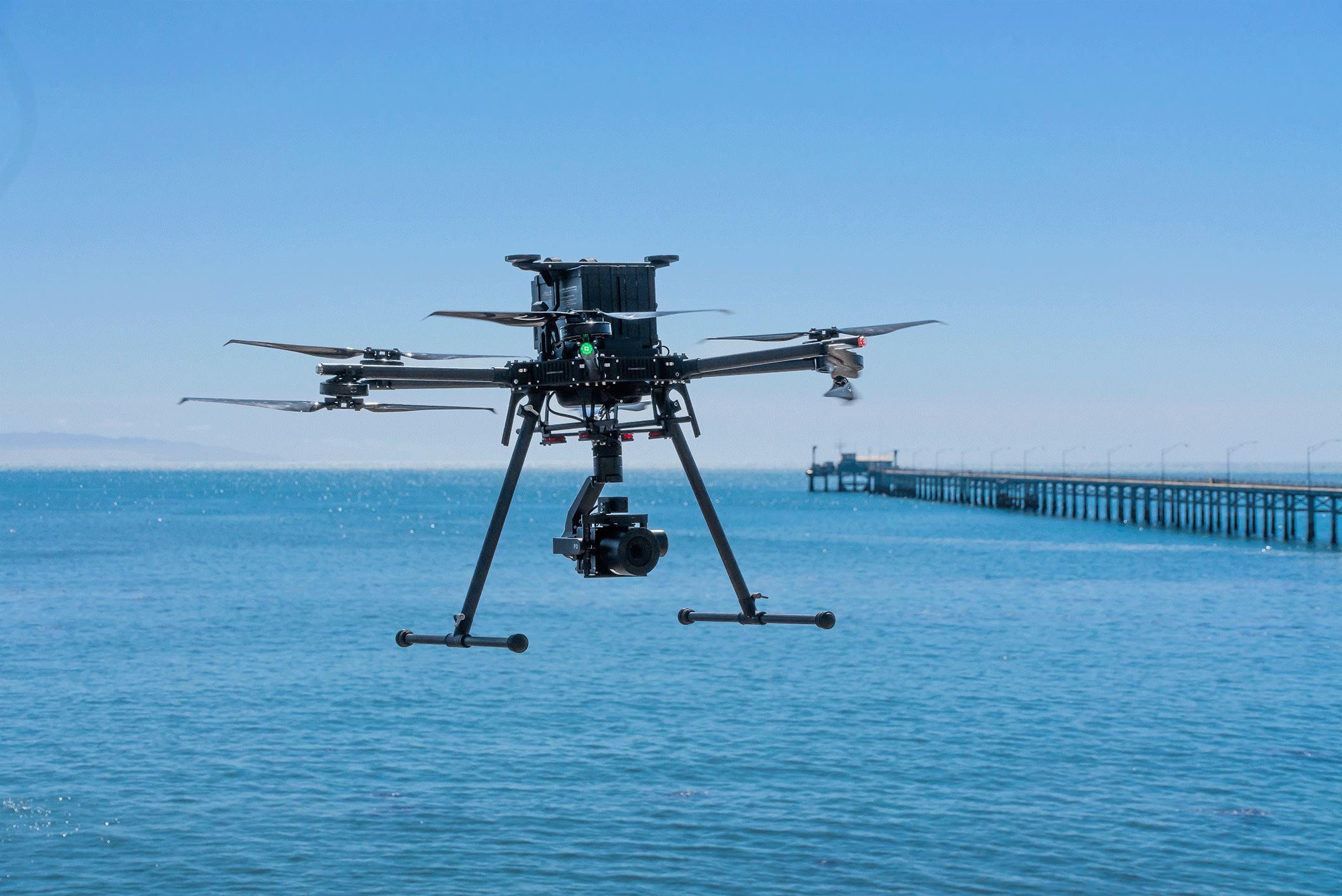 Drone flying over the ocean with pier in the background