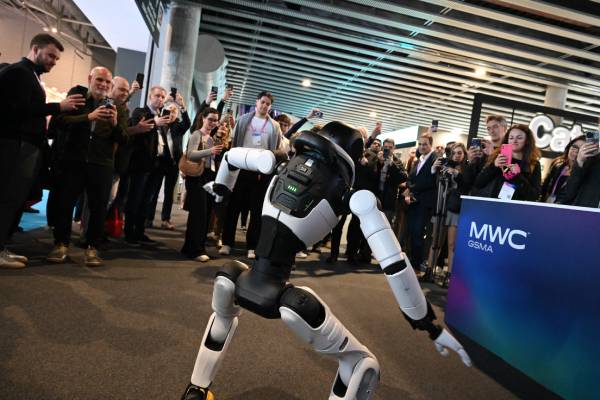 A humanoid robot performs for a crowd taking photos at the MWC GSMA technology event.