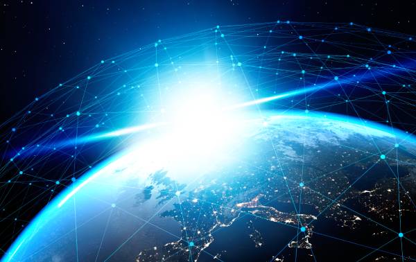 View of Earth from space with a bright sunrise and digital network lines connecting points around the planet.