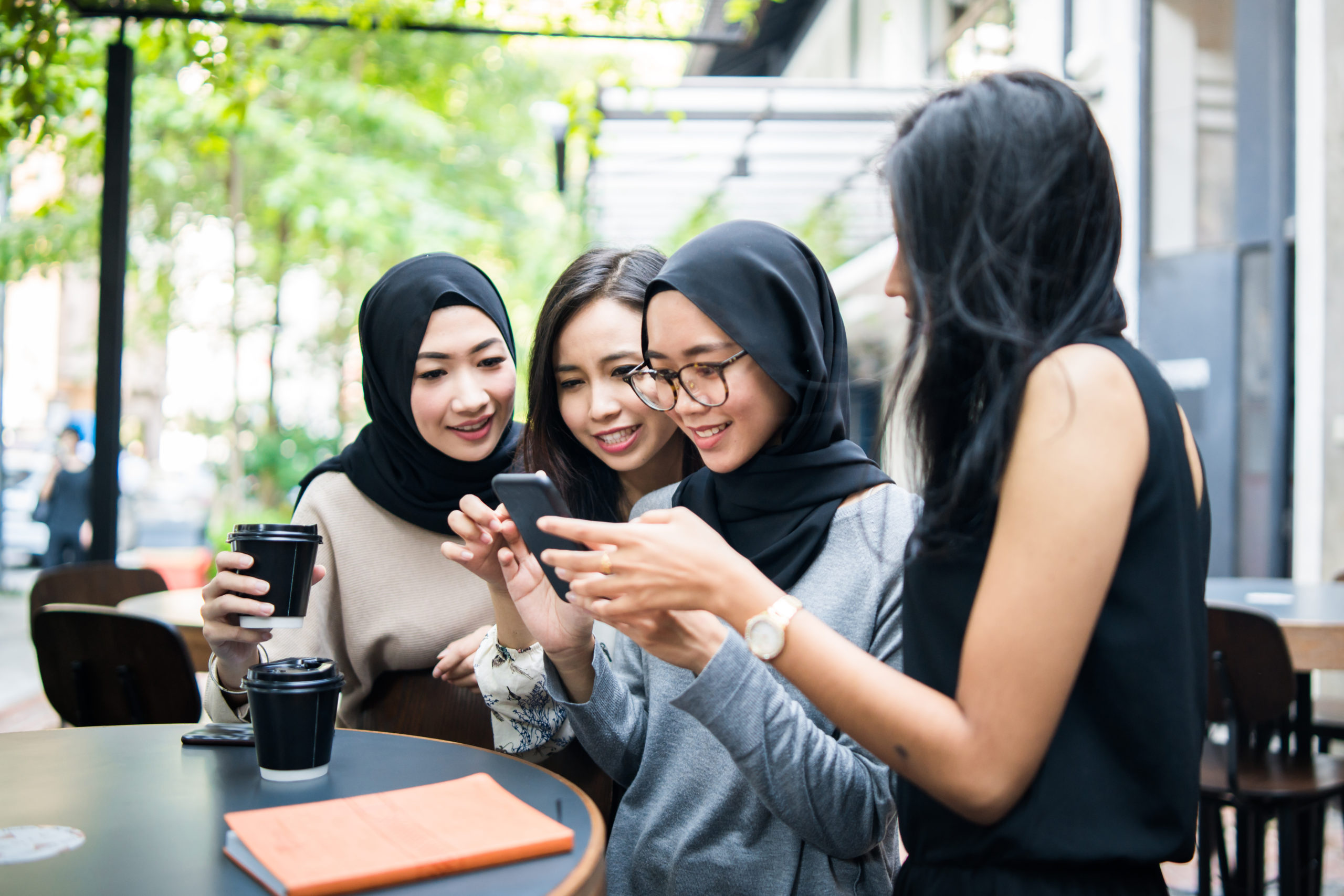 Group of females enjoying coffee and using a mobile phone
