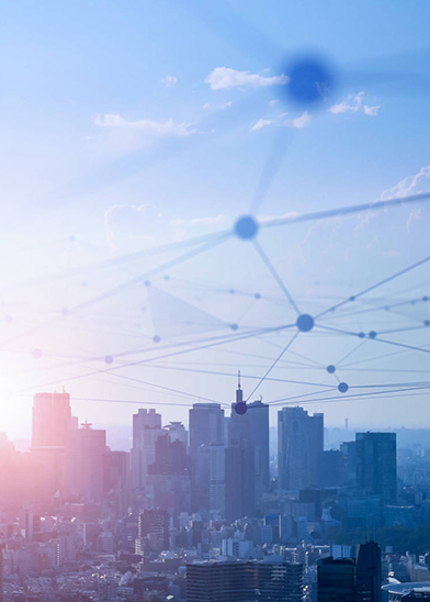 A cityscape during sunset showcases skyscrapers silhouetted against a pastel sky, epitomizing the future of net zero buildings. Overlaid atop are interconnected blue nodes and lines, forming a network pattern that conveys a sense of modern technology and urban connectivity.