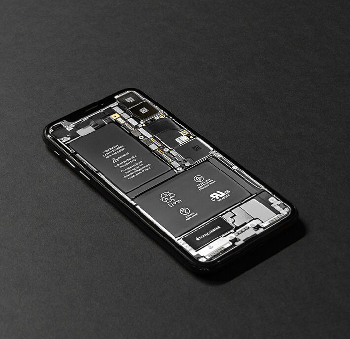 A smartphone lies on a dark surface with its screen displaying a detailed, high-resolution image of its internal components, creating the illusion of a see-through device—a cutting-edge highlight at MWC26 Barcelona.