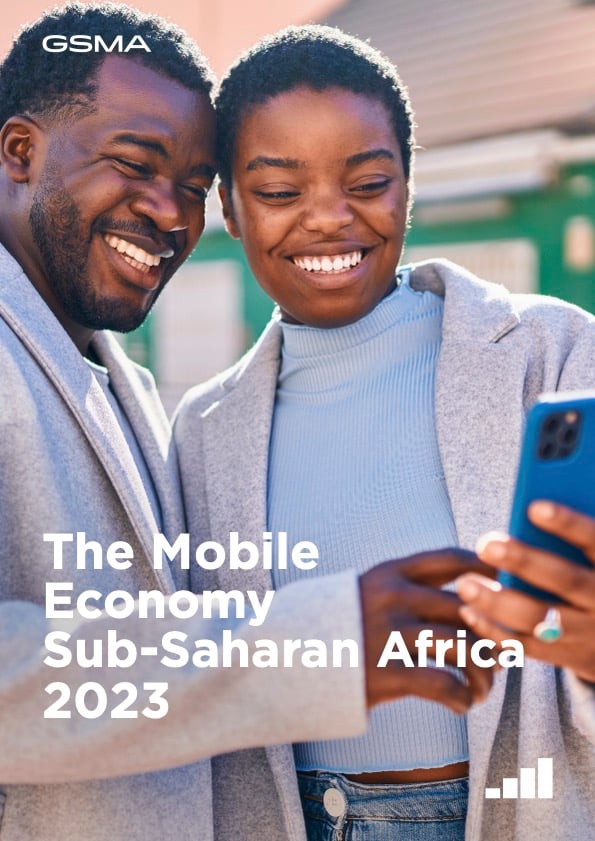 Two smiling Black adults stand close together outdoors, looking at a mobile phone. The woman holds the phone, and both appear happy. Text on the image reads: "The Mobile Economy Sub-Saharan Africa 2023." The GSMA logo is at the top left.