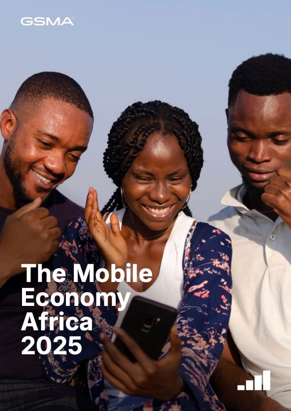 Three young adults, two men and one woman, smile and look at a mobile phone together outdoors. Text on the image reads: "The Mobile Economy Africa 2025" with GSMA logo at the top. The background is a clear blue sky.