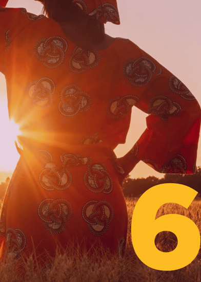 A person in a vibrant orange patterned dress stands in a sunlit field, facing away from the camera. The sun creates a warm glow and lens flare. A large yellow number 6 is placed in the lower right corner of the image.