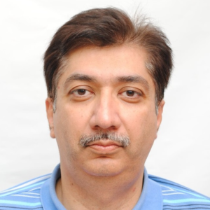 A middle-aged man with a mustache, looking directly at the camera, wearing a light blue shirt against a white background.