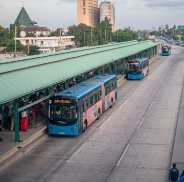 Buses lined up at a city transit station with passengers boarding.