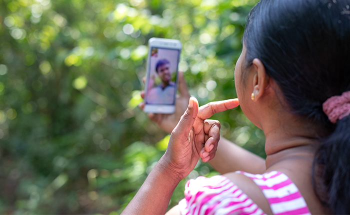 A woman is video calling with someone on her smartphone outdoors.