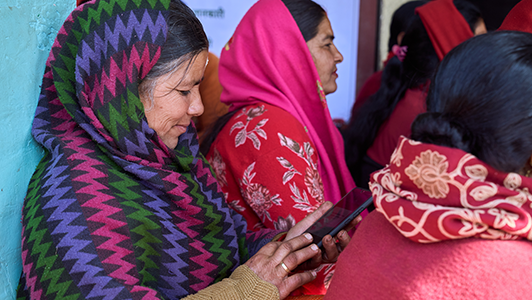 A woman in a striped shawl using a smartphone amidst a group of people.