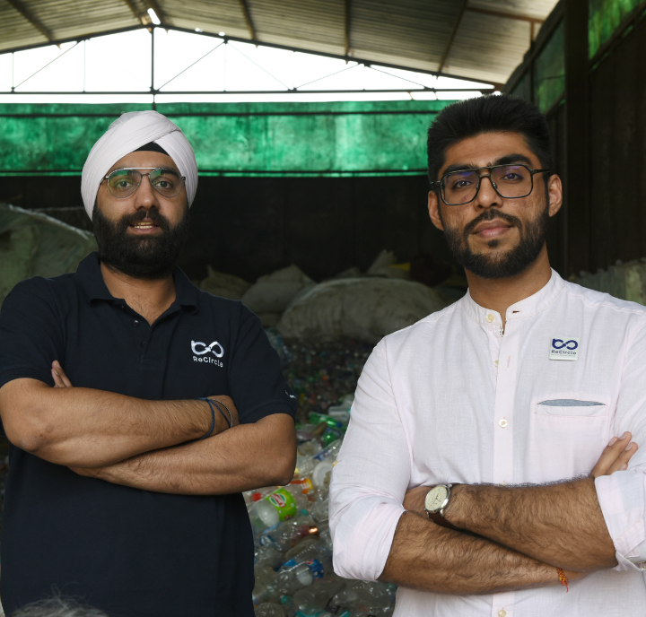 Two individuals standing confidently in a plastic recycling facility.