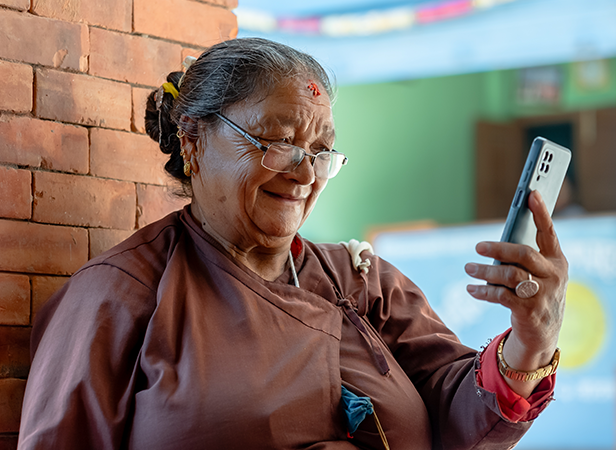 Elderly woman smiling as she looks at her smartphone.