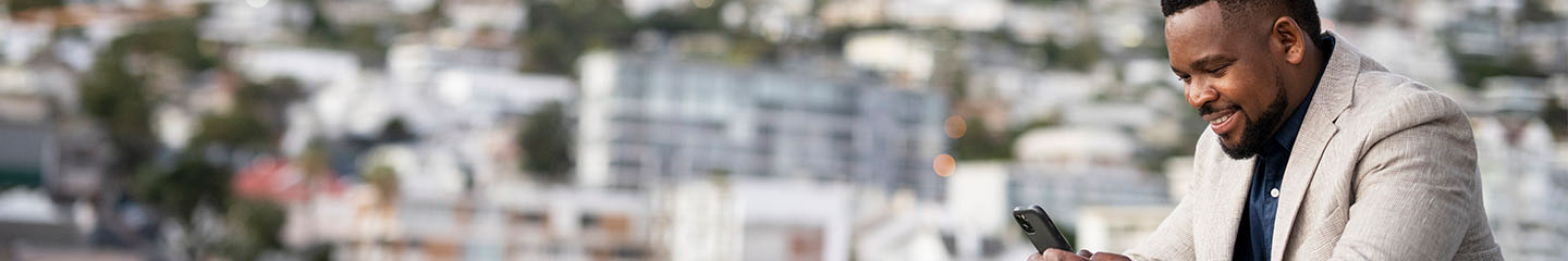 Man smiling at his phone in an urban setting.