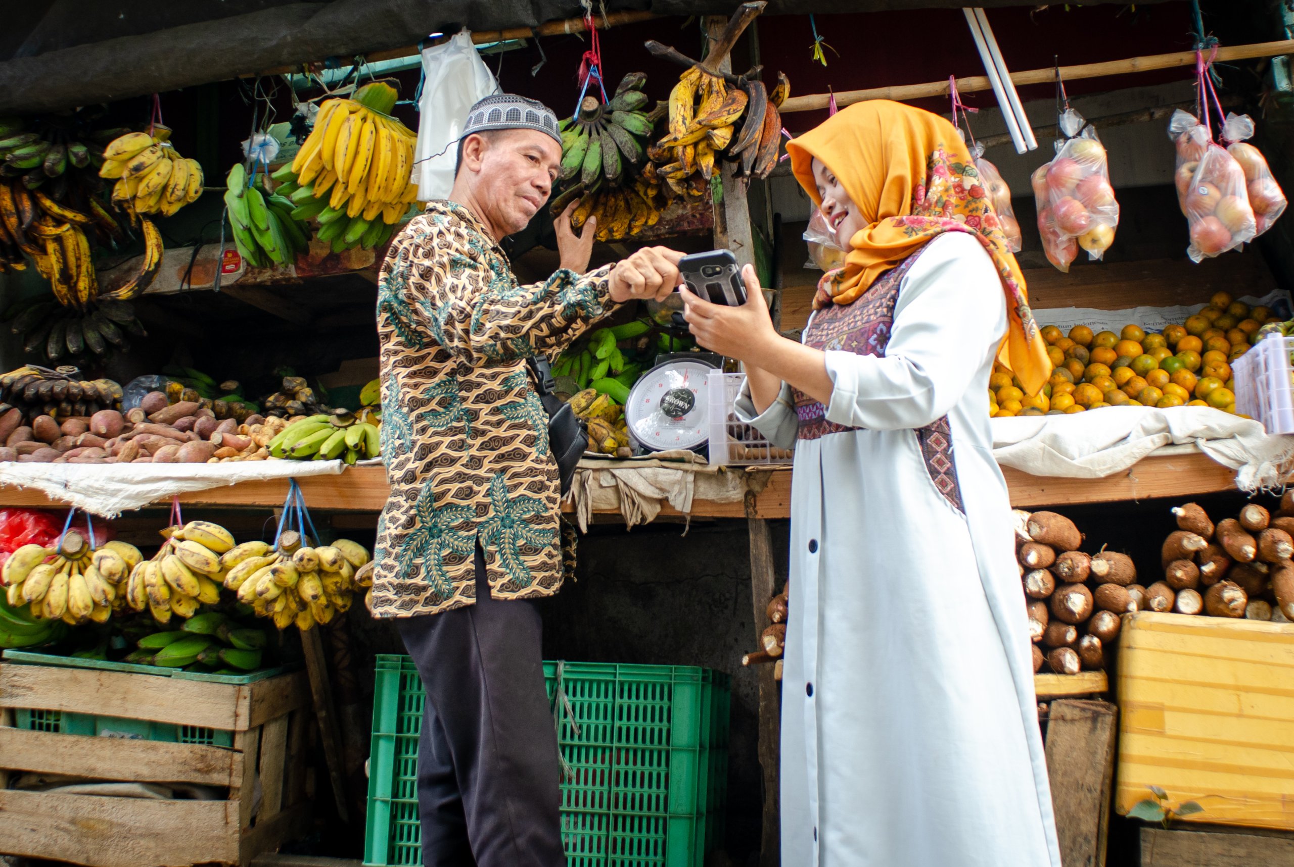 Two individuals engaging in a transaction at a fruit market.