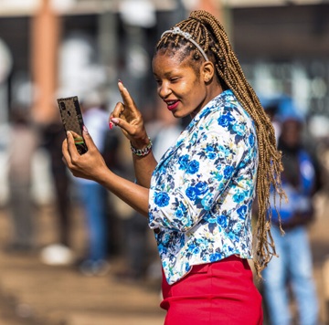A woman smiling while taking a selfie with her smartphone.