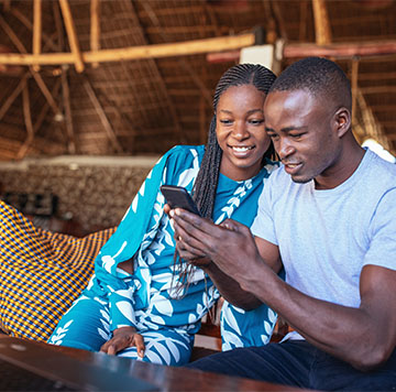 Two individuals smiling and looking at a smartphone together.