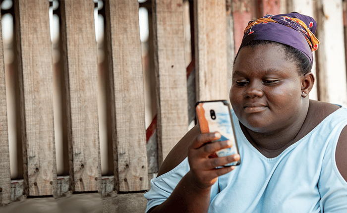 Woman using a smartphone with concentration near a wooden structure.