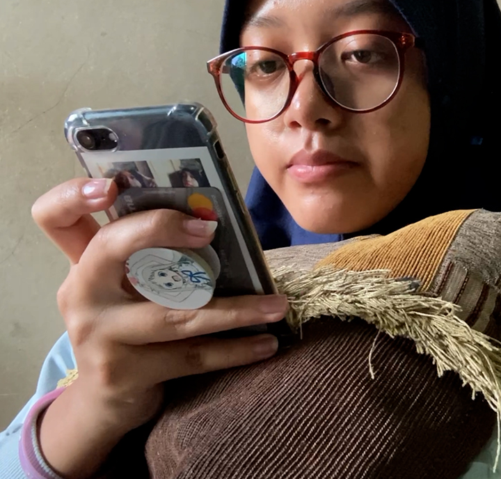 A person wearing glasses and a hijab is looking intently at their smartphone, epitomizing the essence of Connected Women.