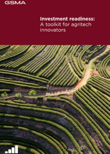 Aerial view of lush, green, terraced farmland with winding paths. The top section has a maroon banner with the GSMA logo and white text: “Investment readiness: A toolkit for agritech innovators.” Small signal icon in the bottom left corner.