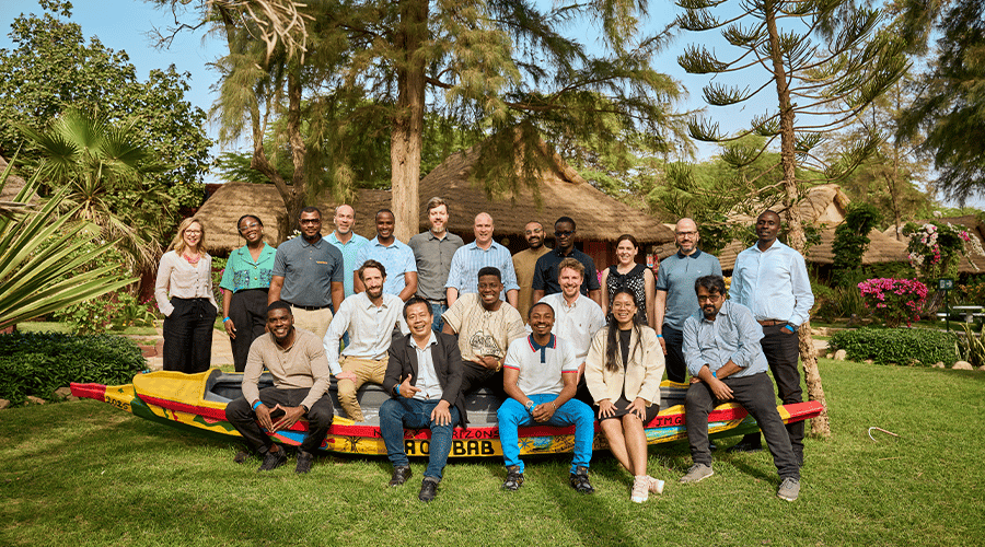 The GSMA AgriTech team and Accelerator cohort members in Senegal during the Field Focus Session, discussing UX design improvements, agent management strategies, and investment readiness while posing on a Senegalese canoe marked 'Baobab Outdoors,' surrounded by stunning landscapes and flowers.