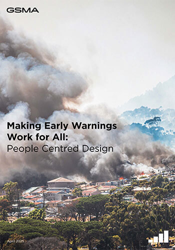A large cloud of dark smoke rises over a suburban area with houses and trees, indicating a fire. Text over the image reads: "Making Early Warnings Work for All: People Centred Design. Tanzania's mobile-enabled early warning systems. GSMA. April 2025.