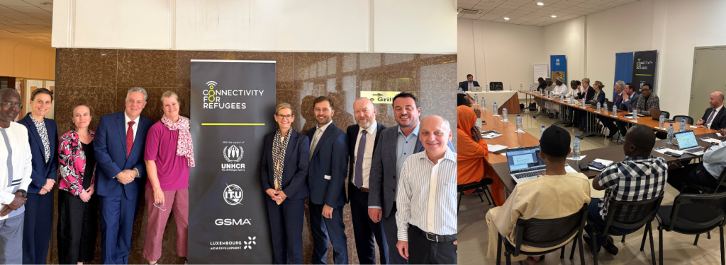 A group of formally dressed people stand smiling beside a “Connectivity for Refugees” banner indoors. Nearby, people of diverse backgrounds sit around a conference table with laptops and documents, attending a meeting or workshop in a bright, modern room.
